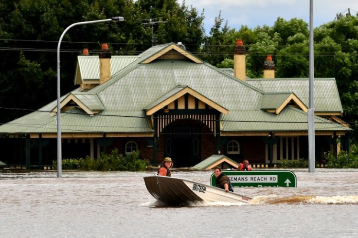 Residents steer boats around flooded houses next to the old Windsor Bridge along the overflowing Hawkesbury River near Sydney