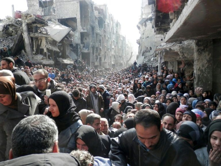 Residents wait for food at a UN distribution point in the Yarmuk refugee camp south of Damascus in 2014