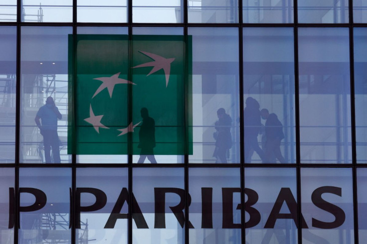 People are silhouetted as they walk behind the logo of BNP Paribas at the bank's building in Issy-les-Moulineaux, near Paris, France, February 3, 2022.