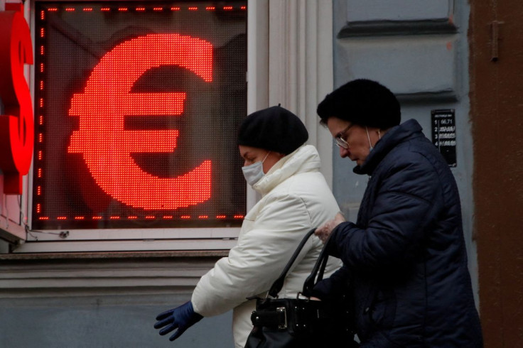 Women walk past a board showing the U.S. dollar and euro signs in a street in Saint Petersburg, Russia February 25, 2022. 