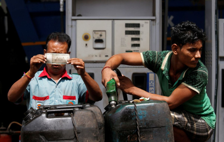 A worker checks a 500 Indian rupee note as a man fills diesel in containers at a fuel station in Kolkata, India, August 14, 2018.