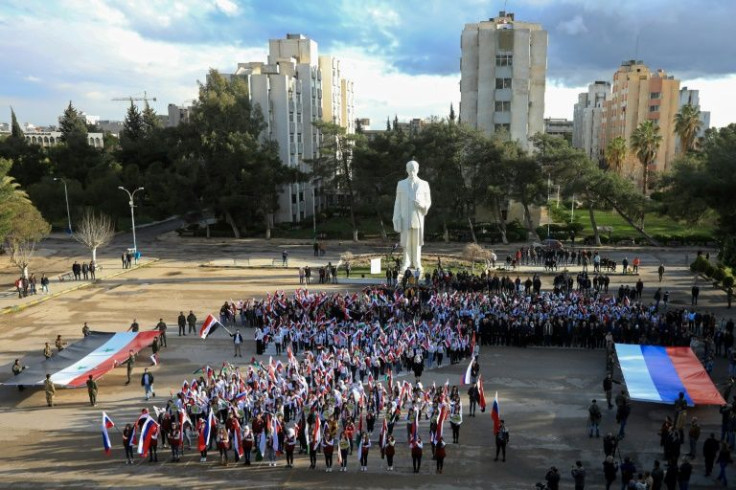 Students wave flags as they gather in support of Russia  at the University of Damascus in the Syrian capital on March 9, 2022