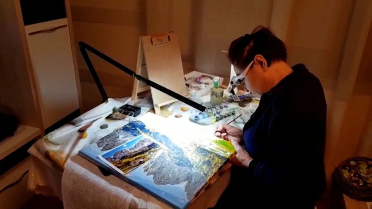 Valeriy, former Ukrainian Chernobyl nuclear plant worker films as his wife Halyna, who also worked at the plant, paints a landscape at their home near Chernihiv, a town they are unable to leave because of the Russian invasion, in this still image obtained