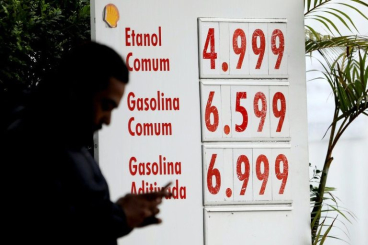 A man passes by a notice board displaying the prices of fuel at a gas station in downtown Sao Paulo, Brazil, in December 2021