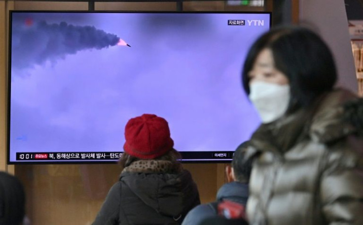 People watch a television screen showing a news broadcast with file footage of a North Korean missile test, at a railway station in Seoul on March 5, 2022