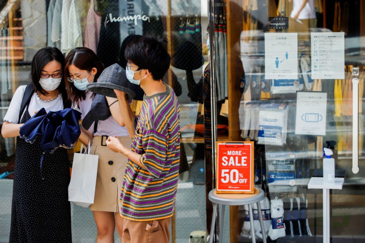 People wearing masks stand outside a shop with infection prevention instructions on it's window in Harajuku shopping area, amid the coronavirus disease (COVID-19) outbreak in Tokyo, Japan August 9, 2021. 