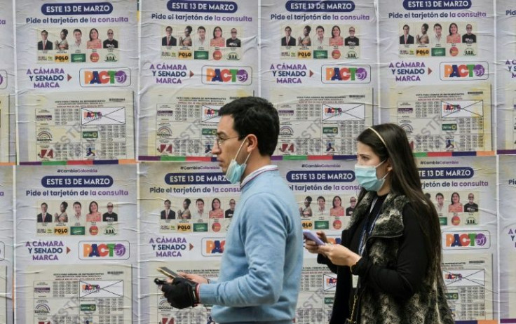 A couple walks past a banner with information on the election in Bogota