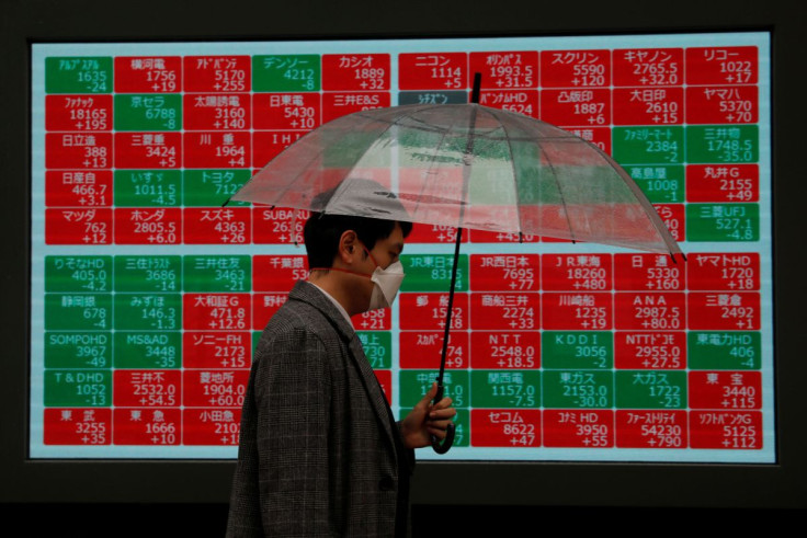 A visitor wearing protective face mask, following an outbreak of the coronavirus, walks past in front of a stock quotation board outside a brokerage in Tokyo, Japan March 2, 2020.   