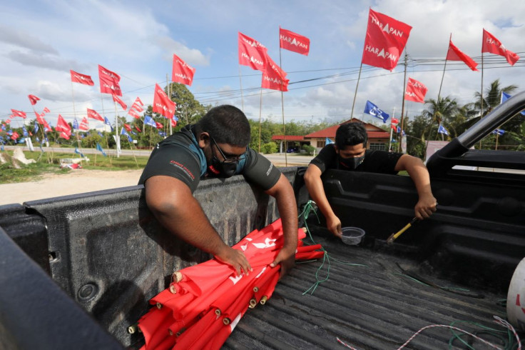 Muhd Faisal Abdullah, 19, (right) places Pakatan Harapan flags on the cargo bed of a truck during the campaign period of Johor state election at Sungai Terap, Muar, Johor, March 4, 2022. Picture taken March 4, 2022.