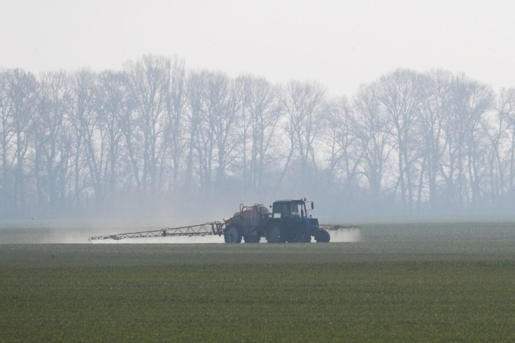 An agricultural worker drives a tractor spreading fertilizers to a field of winter wheat near the village of Husachivka in Kiev region, Ukraine April 17, 2020.