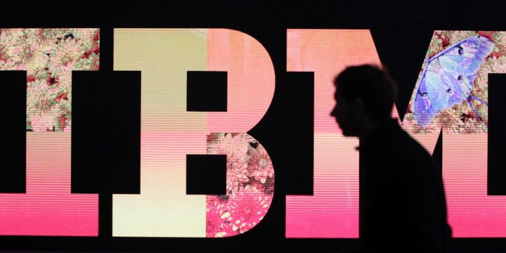 A man passes by an illuminated IBM logo at the CeBIT computer fair in Hanover