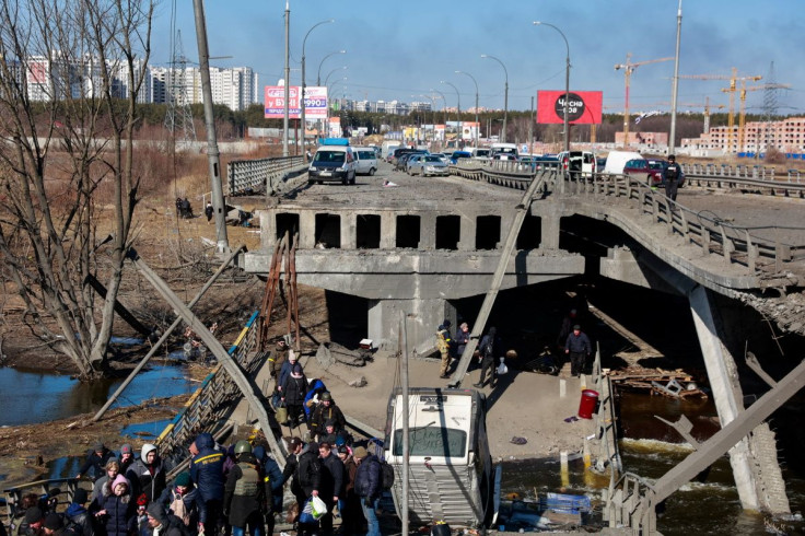 People cross the Irpin river as they evacuate from Irpin town next to a destroyed bridge, amid Russia's invasion of Ukraine, outside of Kyiv, Ukraine March 11, 2022. 