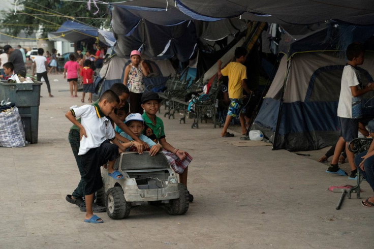 Asylum-seeking migrant children from Central America, who were sent back to Mexico under Title 42 after crossing the border into the U.S. from Mexico, play with a toy car in the public square where hundreds of migrants live in tents, in Reynosa, Mexico, A