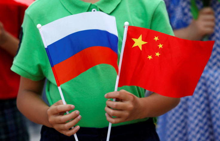 A child holds national flags of Russia and China prior to a welcoming ceremony for Russian President Vladimir Putin outside the Great Hall of the People in Beijing