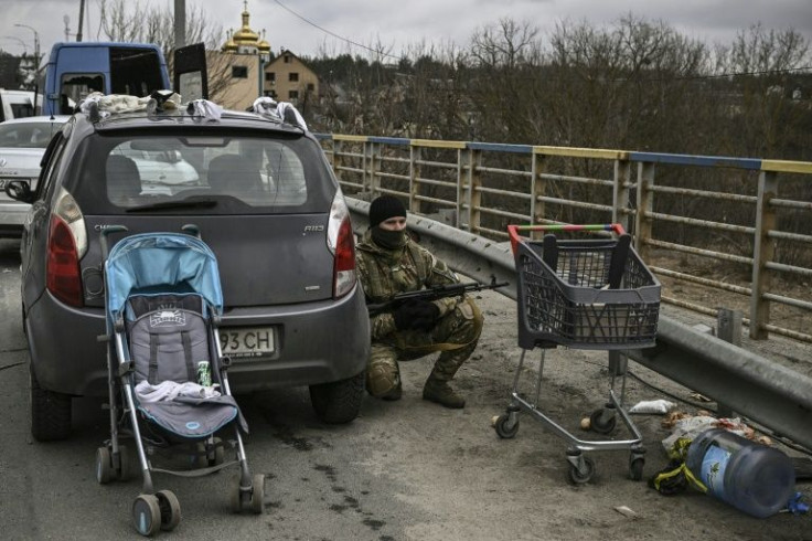 A Ukrainian serviceman takes cover behind a car in Irpin on Sunday. The Kyiv suburb has has witnessed some of the fiercest fighting since Russia invaded Ukraine