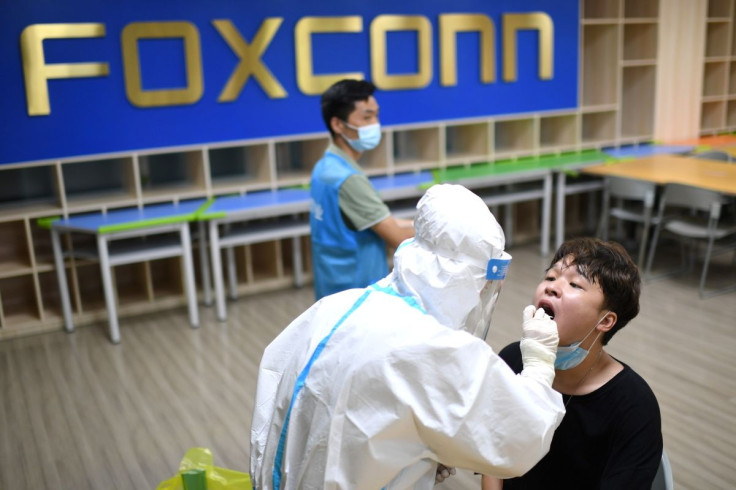 A medical worker in a protective suit collects a swab from a worker for nucleic acid testing at a Foxconn factory, following new cases of the coronavirus disease (COVID-19) in Wuhan, Hubei province, China August 5, 2021. Picture taken August 5, 2021. Chin