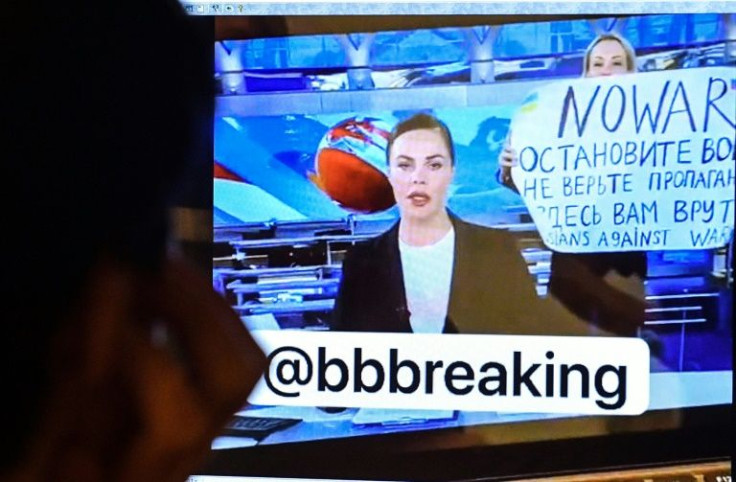A man looks at a computer screen watching a dissenting Russian Channel One employee entering Ostankino on-air TV studio during Russia's most-watched evening news broadcast, holding up a poster which reads as "No War" and condemning Moscow's military actio