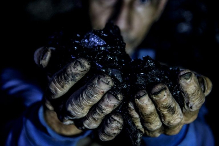 A miner shows off a piece of coal extracted from the Los Parra mine in Lobatera that has a purple glow in his torchlight