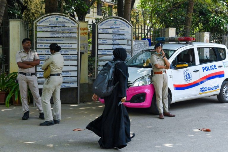 A woman wearing a veil walks past police guarding outside a school in Bangalore, after an Indian court upheld a local ban on the hijab in classrooms