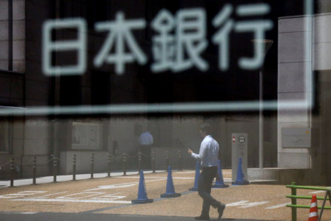 A man is reflected in a sign board of the Bank of Japan building in Tokyo, Japan June 16, 2017. 