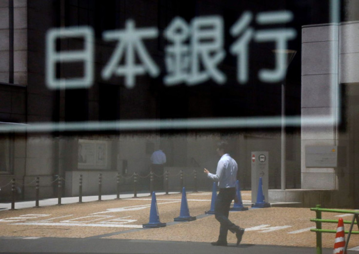 A man is reflected in a sign board of the Bank of Japan building in Tokyo, Japan June 16, 2017.