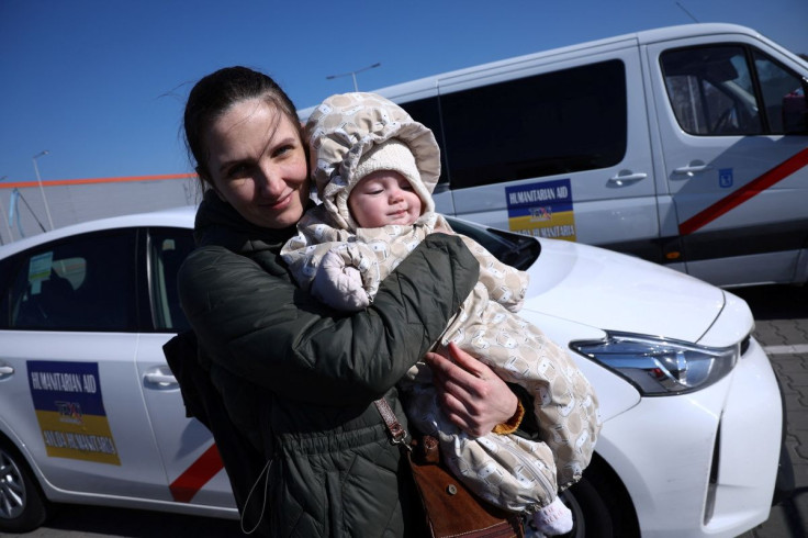 A Ukrainian woman called Olga, 38, holds her 6-month-old daughter Vera near Spanish taxis, in front of the reception center for refugees, following the Russian invasion of Ukraine,in Nadarzyn, Poland, March 14, 2022. Picture taken March 14, 2022.