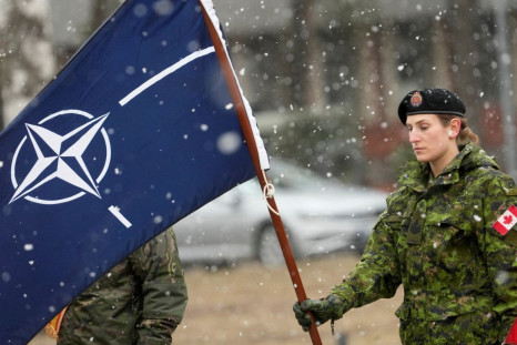 A member of the military holds a flag as they wait for the arrival of Canadian Prime Minister Justin Trudeau along with NATO Secretary-General Jens Stoltenberg in Adazi, Latvia, March 8, 2022. 