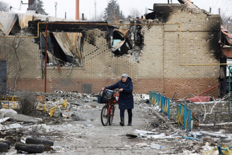 A woman walks with a bicycle next to a building damaged during Ukraine-Russia conflict in the separatist-controlled town of Volnovakha in the Donetsk region, Ukraine March 15, 2022. 