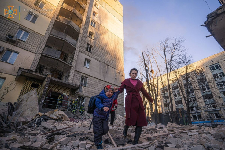 A woman with a child evacuates from a residential building damaged by shelling, as Russia's attack on Ukraine continues, in Kyiv, Ukraine, in this handout picture released March 16, 2022.  Press service of the State Emergency Service of Ukraine/Handout vi