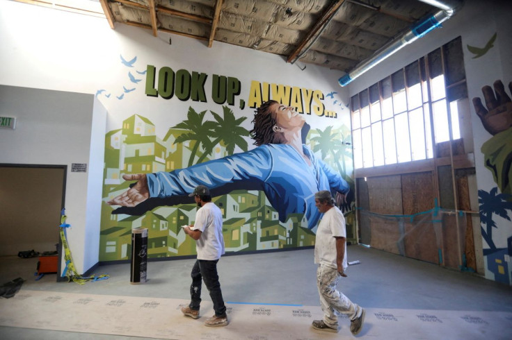 Construction workers pass in front of a mural at Carnegie Shelter, which is currently under construction in Santa Ana, California, U.S. March 2, 2022. Picture taken March 2, 2022.