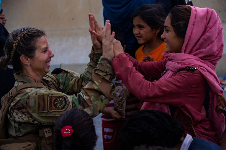 A U.S Airman with the Joint Task Force-Crisis Response high fives a child after helping reunite their family at Hamid Karzai International Airport, in Kabul, Afghanistan, August 20, 2021. Cpl. Davis Harris/U.S. Marine Corps/Handout via