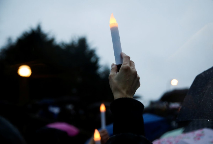 A person holds a battery-powered candle in the rain during a "Stop Asian Hate" rally and vigil to remember the Atlanta shooting victims at Bellevue Downtown Park in Bellevue, Washington, U.S. March 20, 2021.  