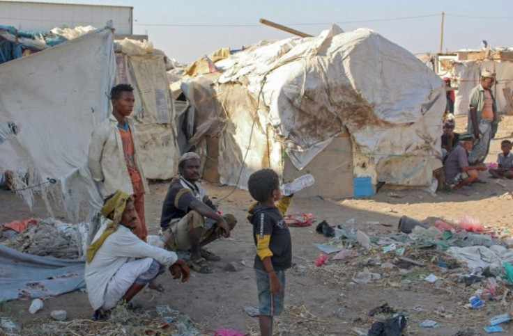 Internally displaced people sit by their tents at a camp north of Yemen's southern city of Aden, on March 6, 2022