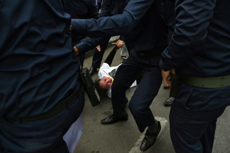 A relative of a jailed opposition member clashes with security forces during a protest in front of a court in Phnom Penh