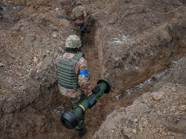 A Ukrainian service member walks along a trench with a Javelin missile system a at a position on the front line in the north Kyiv region