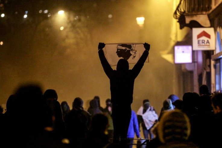 A protester holds a Corsican flag during clashes with police following a rally in support to Corsican nationalist figure Yvan Colonna a week after he was attacked in prison, in Bastia, Corsica, on March 13, 2022.Colonna, who is serving a life sentence for