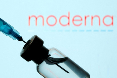 A vial and sryinge are seen in front of a displayed Moderna logo in this illustration taken January 11, 2021. 