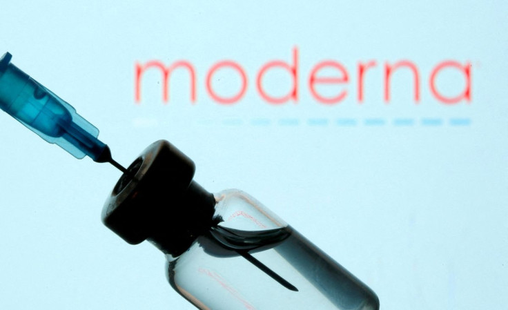 A vial and sryinge are seen in front of a displayed Moderna logo in this illustration taken January 11, 2021. 