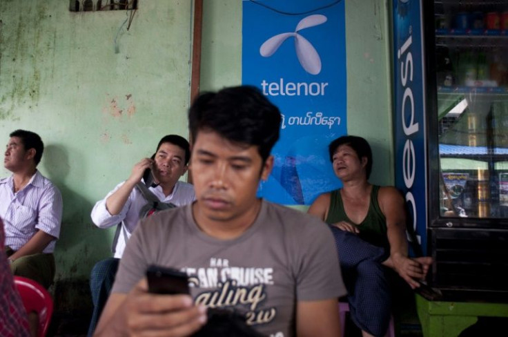 A man uses a phone in front of a Telenor advertising board in Yangon