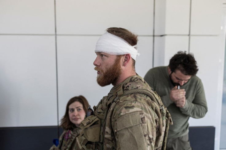 Red Taylor, Alexis Antilla and Rob, members of a group of U.S. volunteer fighters who have taken up arms alongside Ukrainian soldiers, gather in front of a hospital in the town of Brovary, as Russia's invasion of Ukraine continues, near Kyiv, Ukraine, Mar