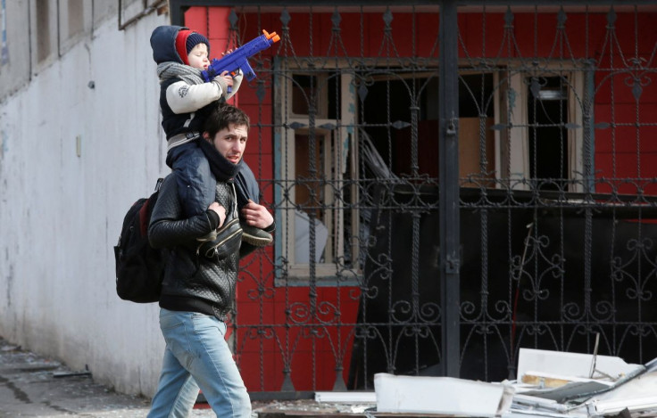 A child sits on the shoulders of a man near a building damaged during Ukraine-Russia conflict in the besieged southern port city of Mariupol, Ukraine March 20, 2022.