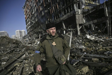 An Orthodox priest picks his way through the rubble, muttering prayers and cursing the 'Russian terrorists'