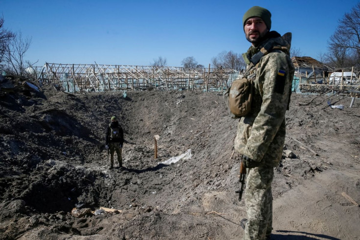 Ukrainian service members inspect a shell crater, as the Russian invasion continues, in a village on the front line in the east Kyiv region, Ukraine March 21, 2022. 