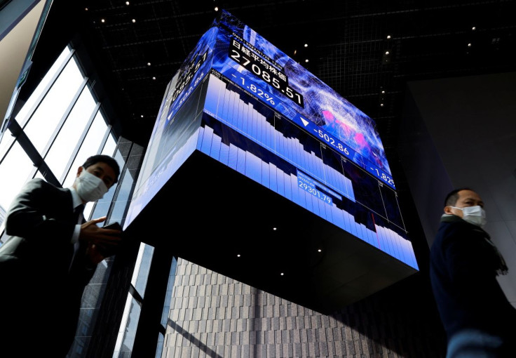 Men wearing protective face masks walk under an electronic board showing Japanâs Nikkei share average inside a conference hall, amid the coronavirus disease (COVID-19) pandemic, in Tokyo, Japan January 25, 2022.  