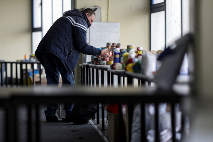 A man that fled the Russian invasion of Ukraine picks canned goods from a pile inside a Bucharest convention centre that offers a one-stop shop fuelled by donations, in Bucharest, Romania, March 21, 2022. Picture taken March 21, 2022. Inquam Photos/Octav 