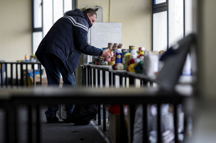 A man that fled the Russian invasion of Ukraine picks canned goods from a pile inside a Bucharest convention centre that offers a one-stop shop fuelled by donations, in Bucharest, Romania, March 21, 2022. Picture taken March 21, 2022. Inquam Photos/Octav