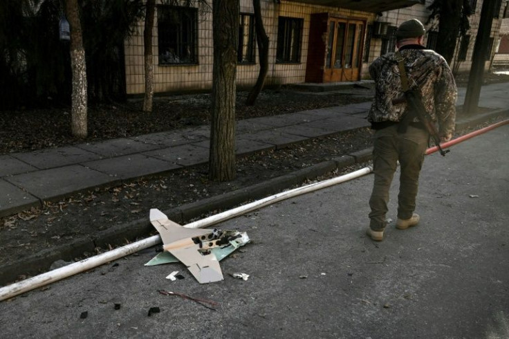 A Ukrainian serviceman stands next to a downed Russian drone