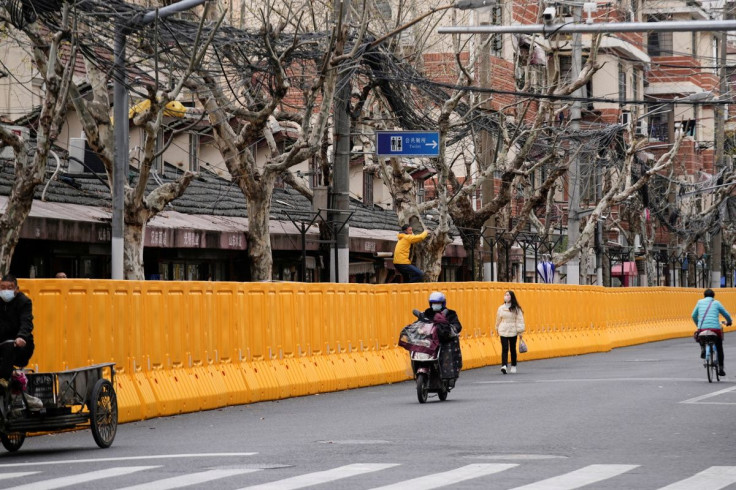 A man climbing a tree looks over barriers, which have been built to separate buildings from a street, amid the coronavirus disease (COVID-19) pandemic in Shanghai, China March 22, 2022.