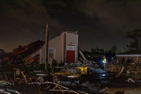 People walk in front of a damaged building after a tornado struck in the Arabi neighborhood, St. Bernard Parish, New Orleans, Louisiana March 22, 2022. 