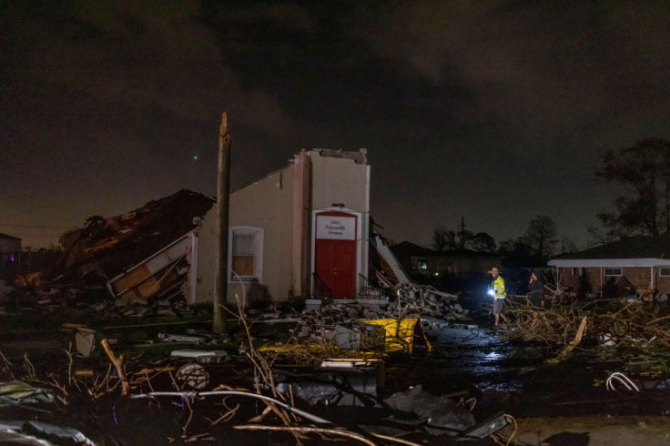 People walk in front of a damaged building after a tornado struck in the Arabi neighborhood, St. Bernard Parish, New Orleans, Louisiana March 22, 2022. 